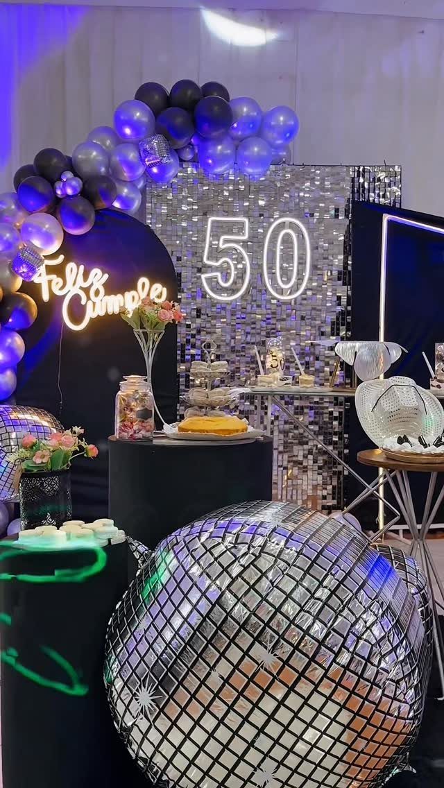 Birthday party decoration with silver sequins, neon 50 sign, and disco balls.