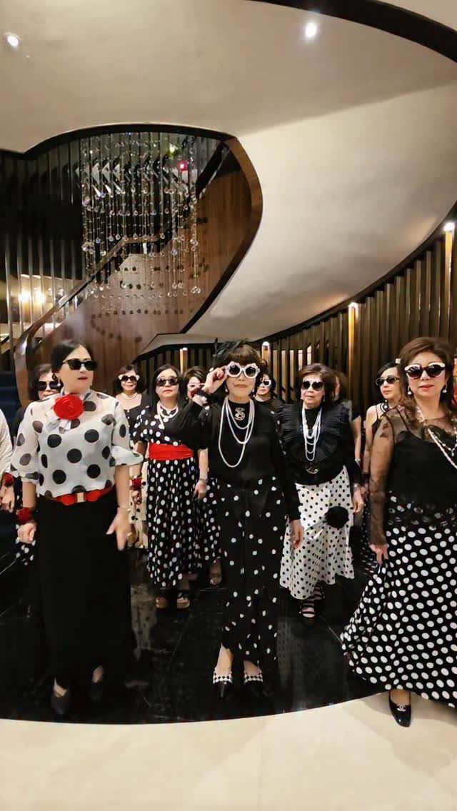 Women in retro polka dot dresses and sunglasses posing in a modern lobby