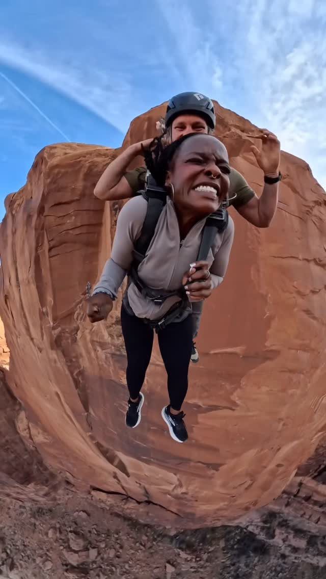 Woman with terrified expression tandem skydiving over red rock desert formations