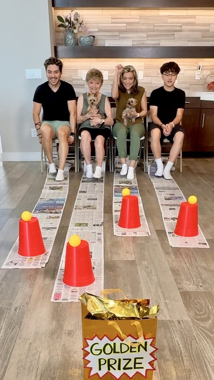 Four people sitting behind newspaper lanes with red cones and a golden prize bag.