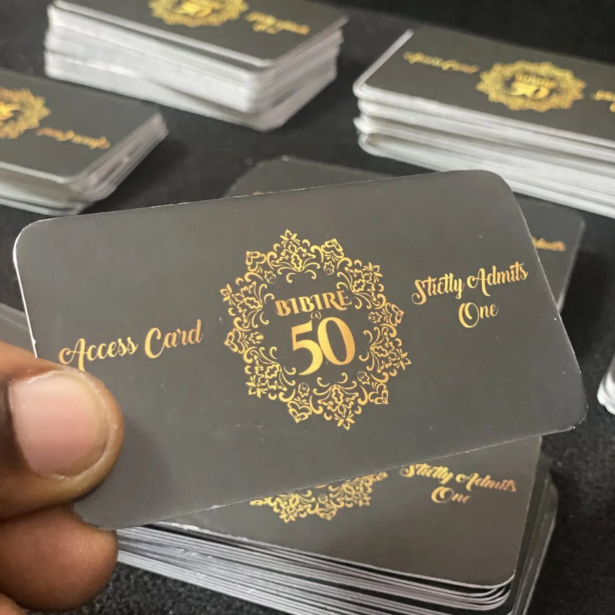 Black and gold 50th birthday access cards held by a hand