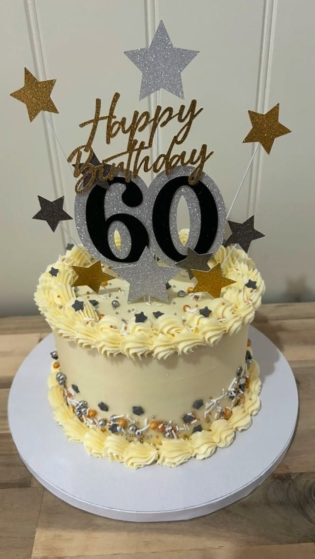 White frosted birthday cake with piped borders and a gold 60th birthday topper.