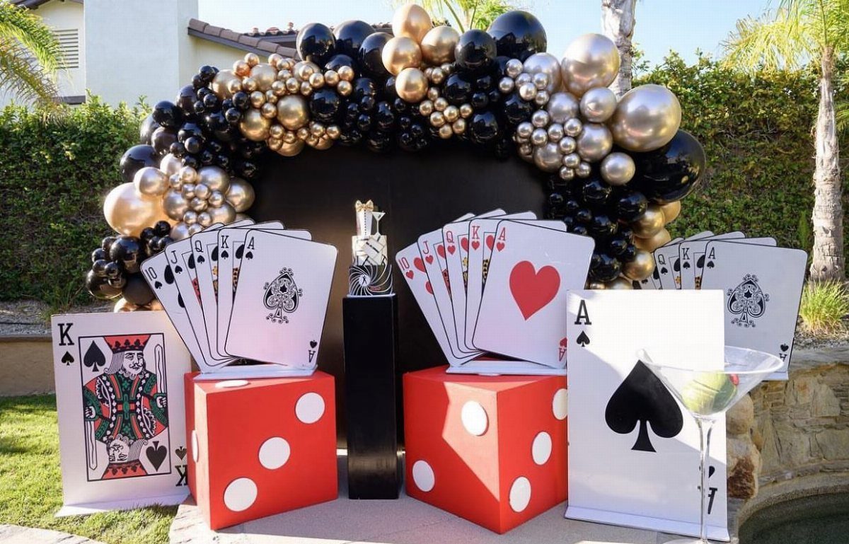 Casino themed party decorations with giant dice, playing cards, and gold balloons.