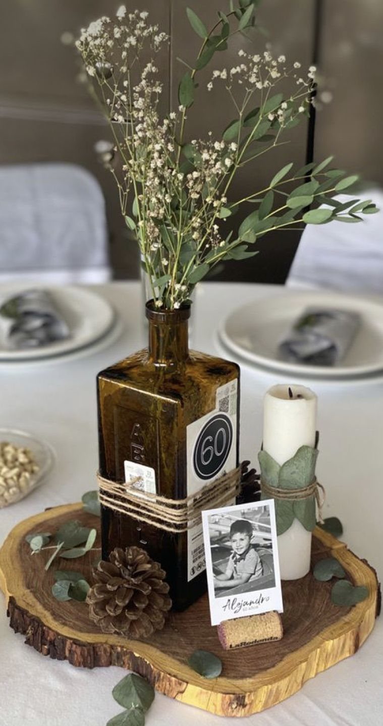 Rustic 60th birthday centerpiece with brown bottle, white candle, and wood slice base.
