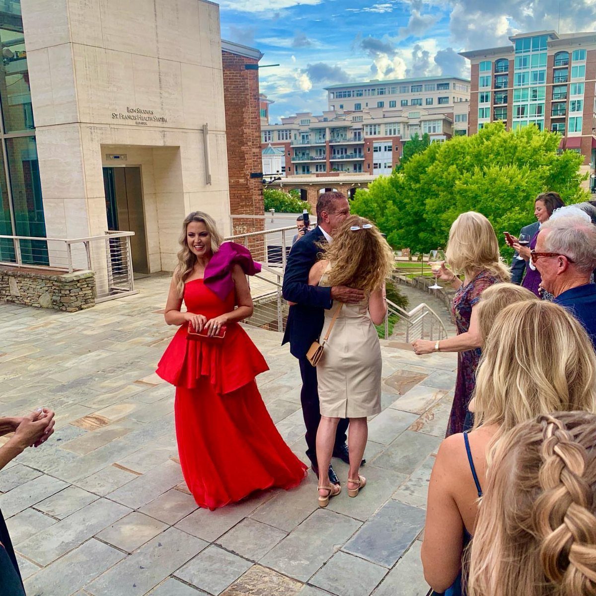 Woman wearing a formal red gown with ruffles at an outdoor party.