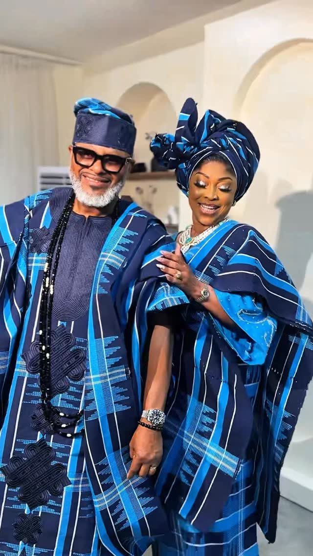 Man and woman in matching blue and black striped traditional Nigerian attire posing.