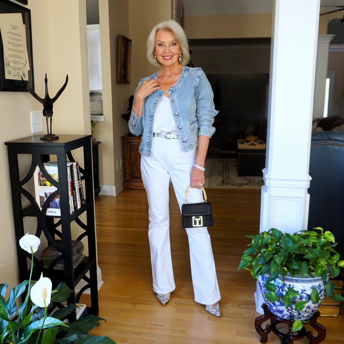 Mature woman wearing a denim jacket, white top, and white wide-leg trousers.