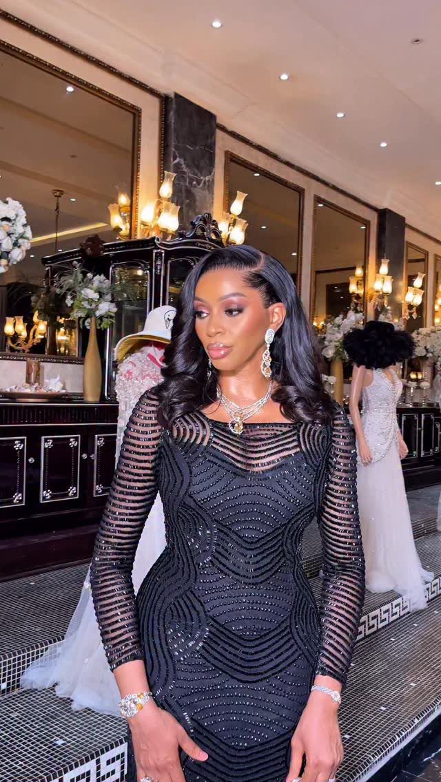 Woman in a shimmering black beaded long-sleeved dress posing in a luxury room