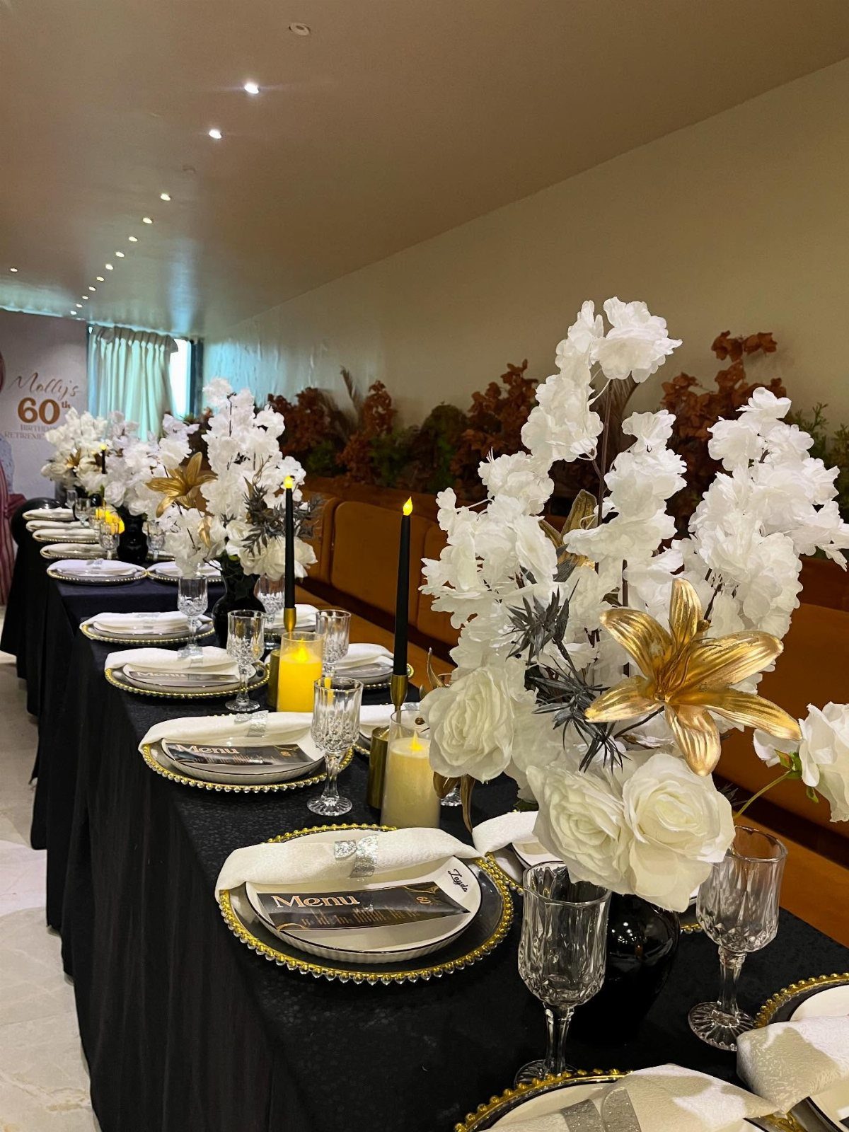 Elegant banquet table setting with white and gold flowers and black candles.