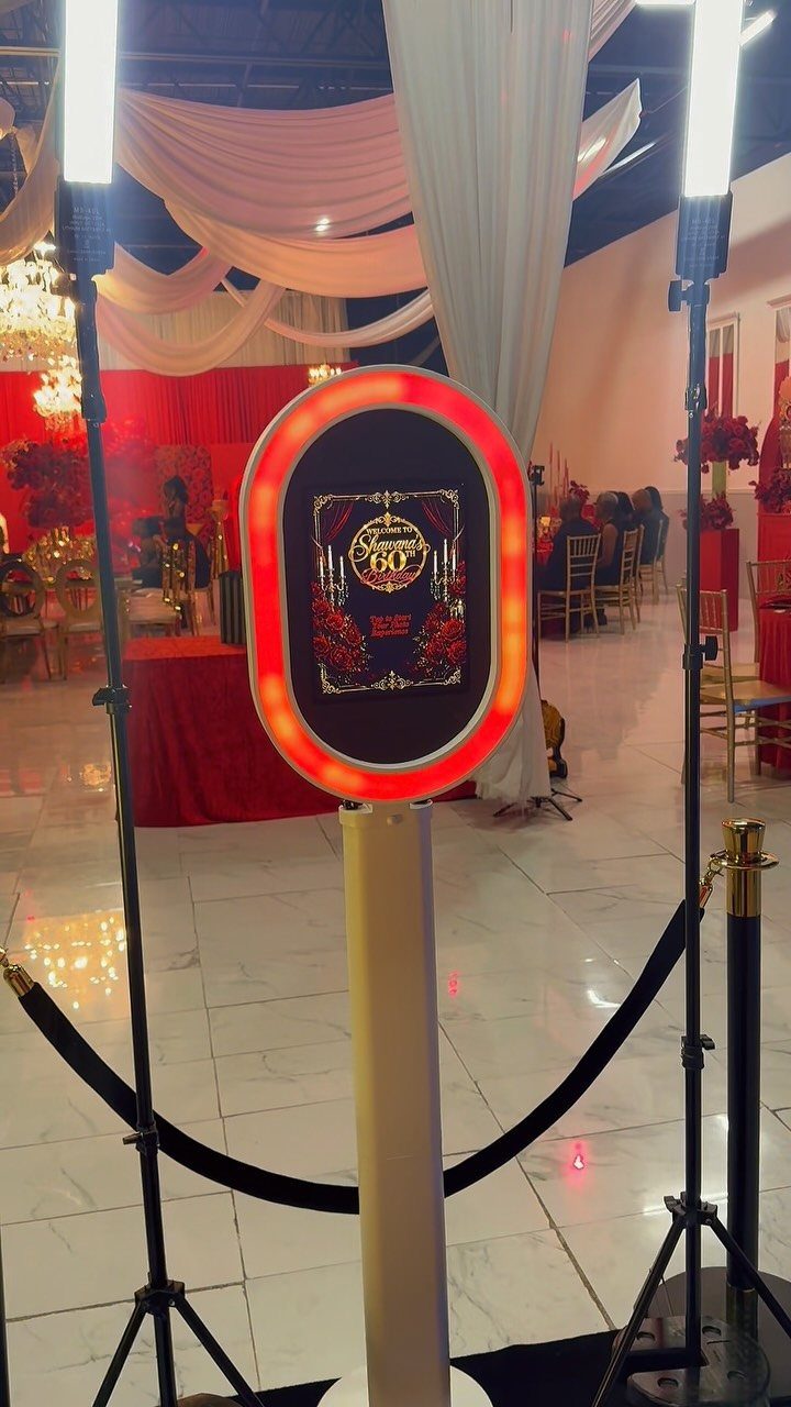 Digital photo booth kiosk with red lighting in a decorated 60th birthday venue