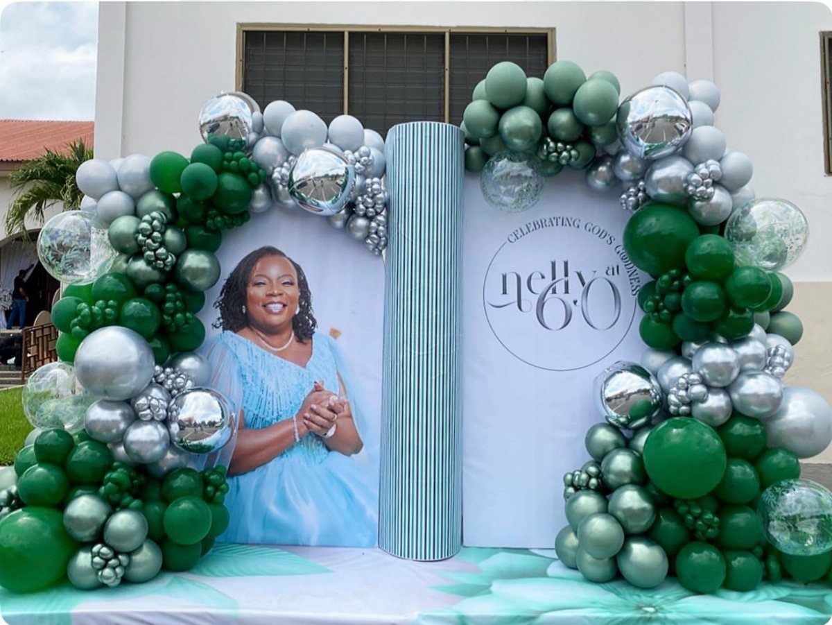 Open book party backdrop with a woman's portrait and 60th birthday text, framed by balloons.