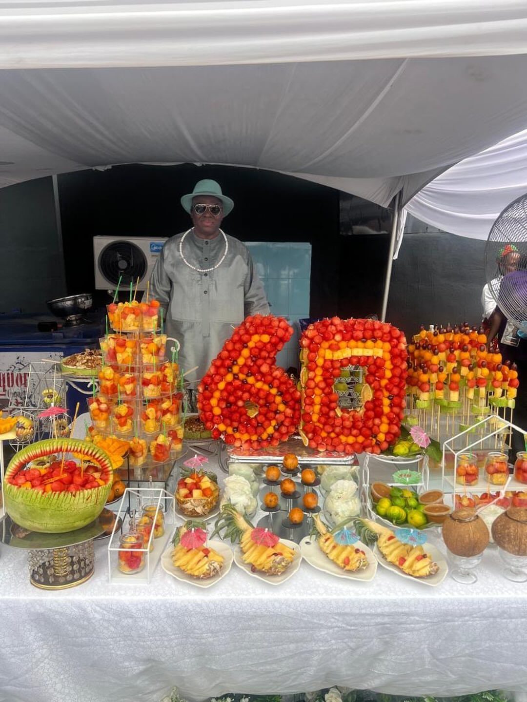 Fruit display arranged as the number 60 on a table under a tent.