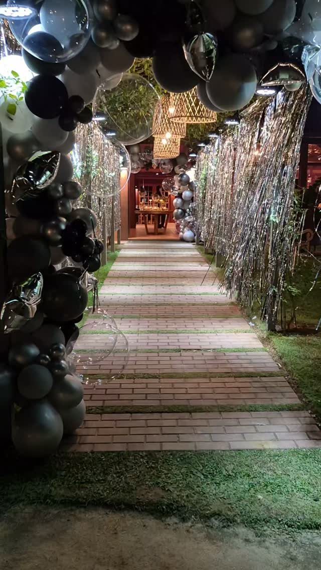Brick pathway decorated with silver and black balloons and shimmering tinsel curtains.