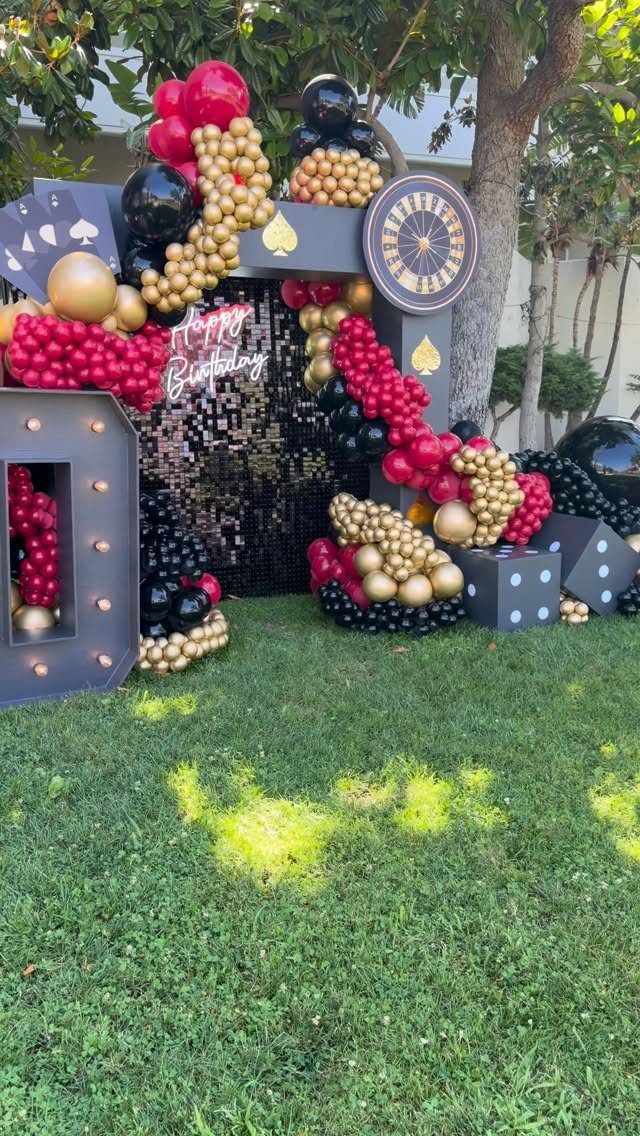 Casino themed birthday decoration with red and gold balloons, dice, and roulette wheel.
