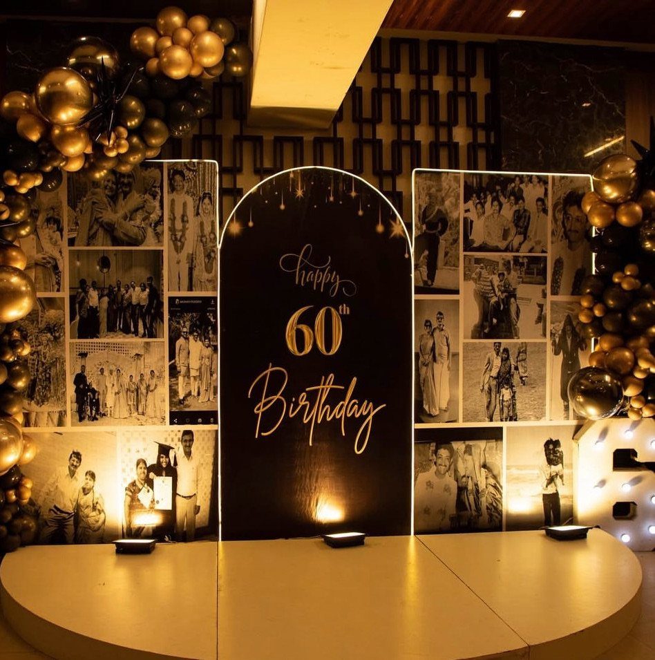 60th birthday party backdrop with gold balloons and walls of black and white photos