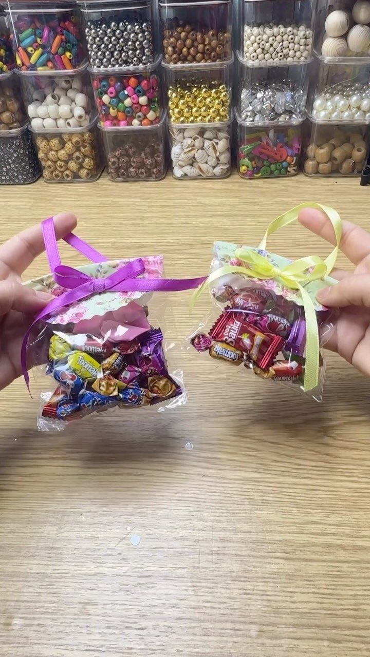 Two clear bags of assorted wrapped candies tied with purple and green ribbons.