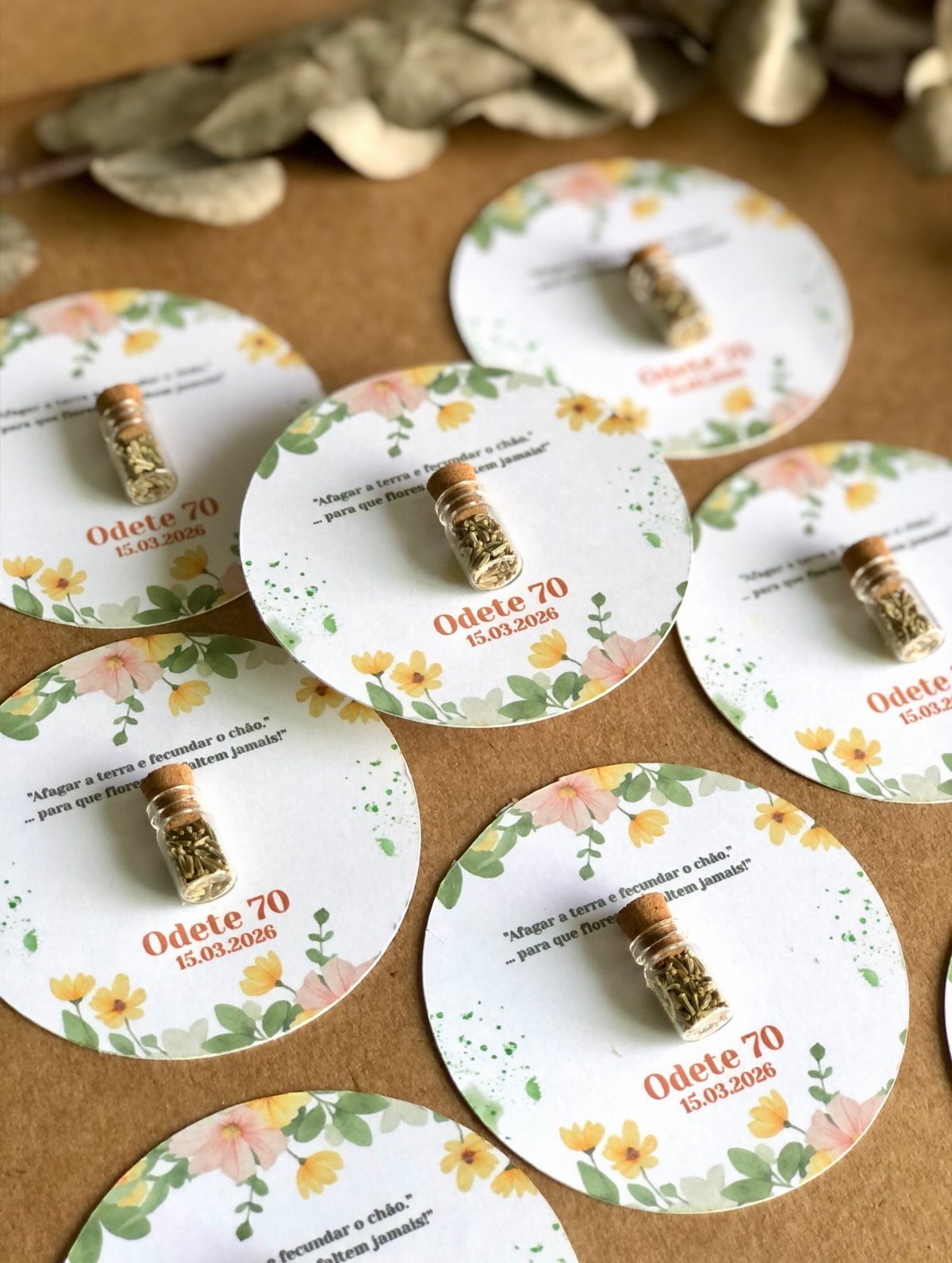 Small herb vials on floral circular cards for Odete's 70th birthday celebration.