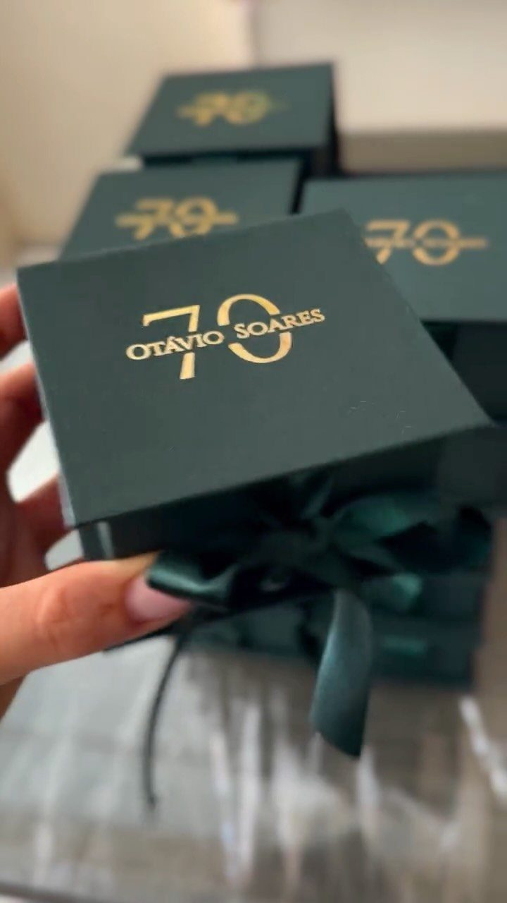 Dark green gift boxes with gold 70th birthday lettering and satin ribbons.