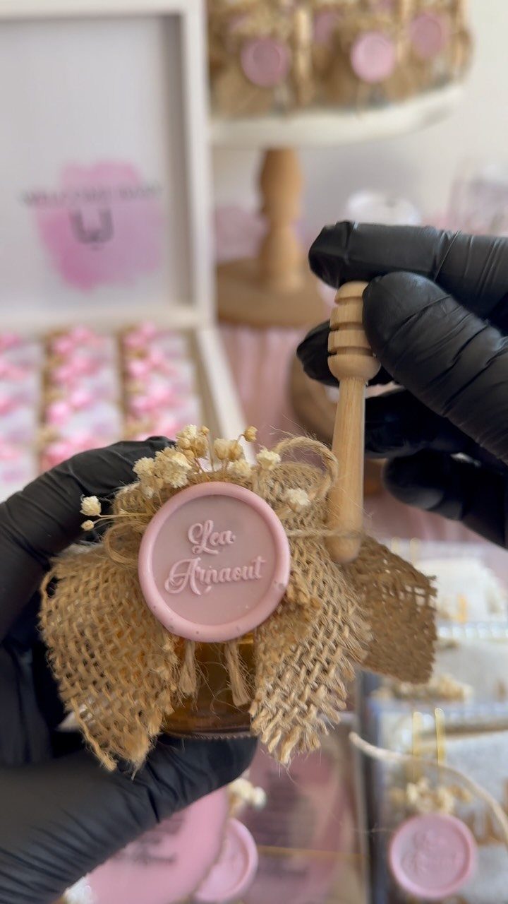 Small honey jar favor with burlap, pink wax seal, and wooden honey dipper.