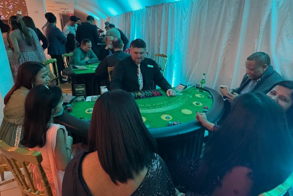 People playing blackjack at a green gaming table in a blue-lit event space