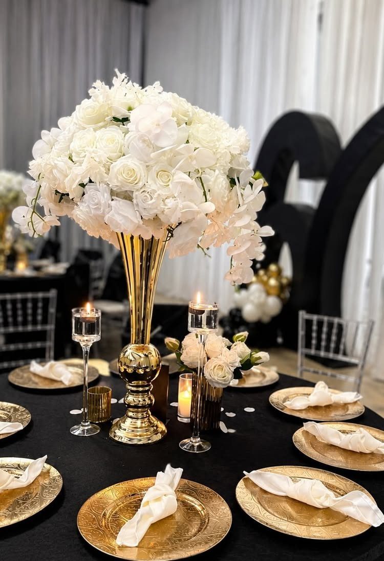 Elegant party table with gold plates and white floral centerpiece against black numbers.
