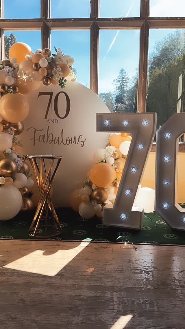70th birthday party decorations with gold balloons and large illuminated number 70 signs