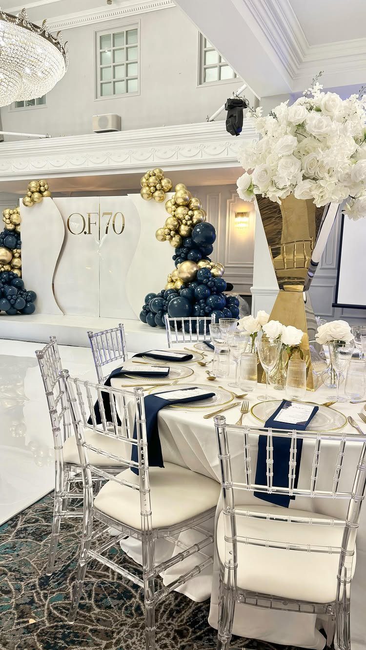 Elegant 70th birthday party setup with navy and gold balloons and white table settings.