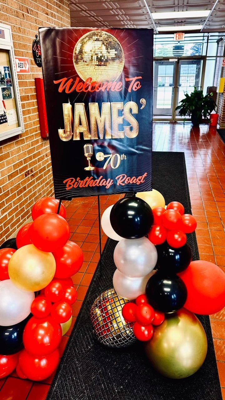 Birthday roast banner for James' 70th with red, gold, and black balloons.