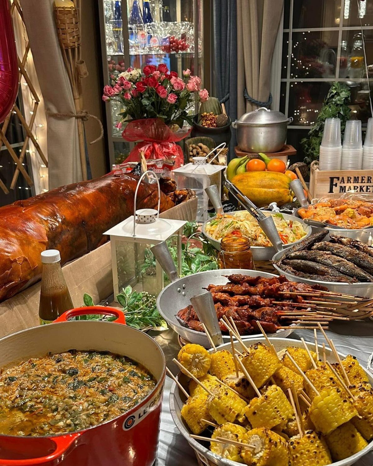 Buffet spread with roasted pig, corn skewers, and various dishes for a celebration.