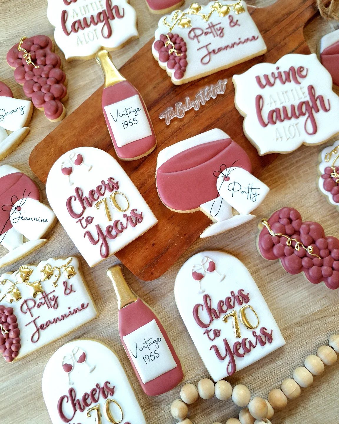 Wine themed sugar cookies celebrating a 70th birthday on a wooden board