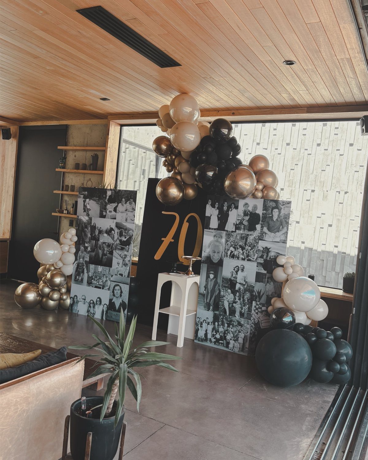 70th birthday party decoration with gold balloons, photo collages, and gold number 70