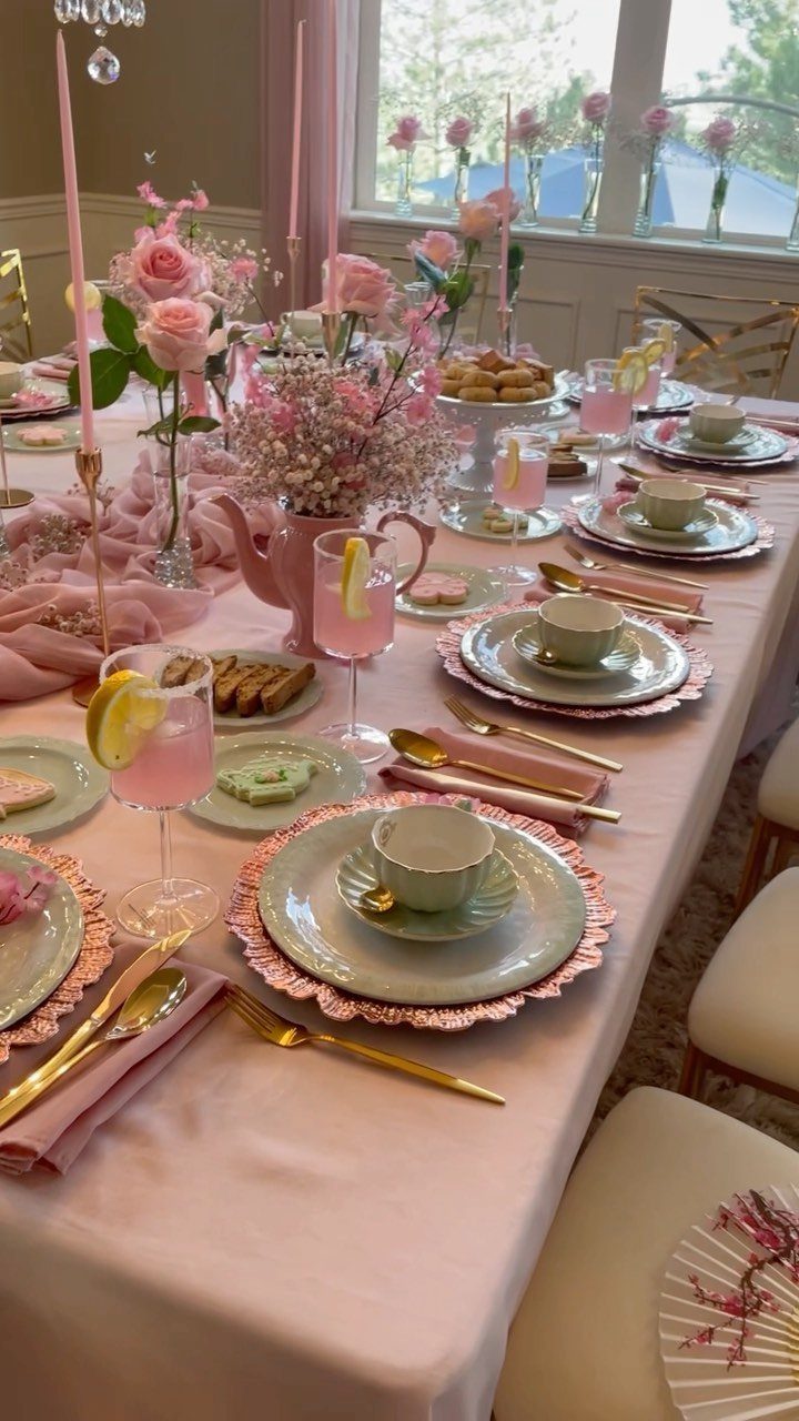 Elegant tea party table setting with pink roses, teapot, and pastel teacups.