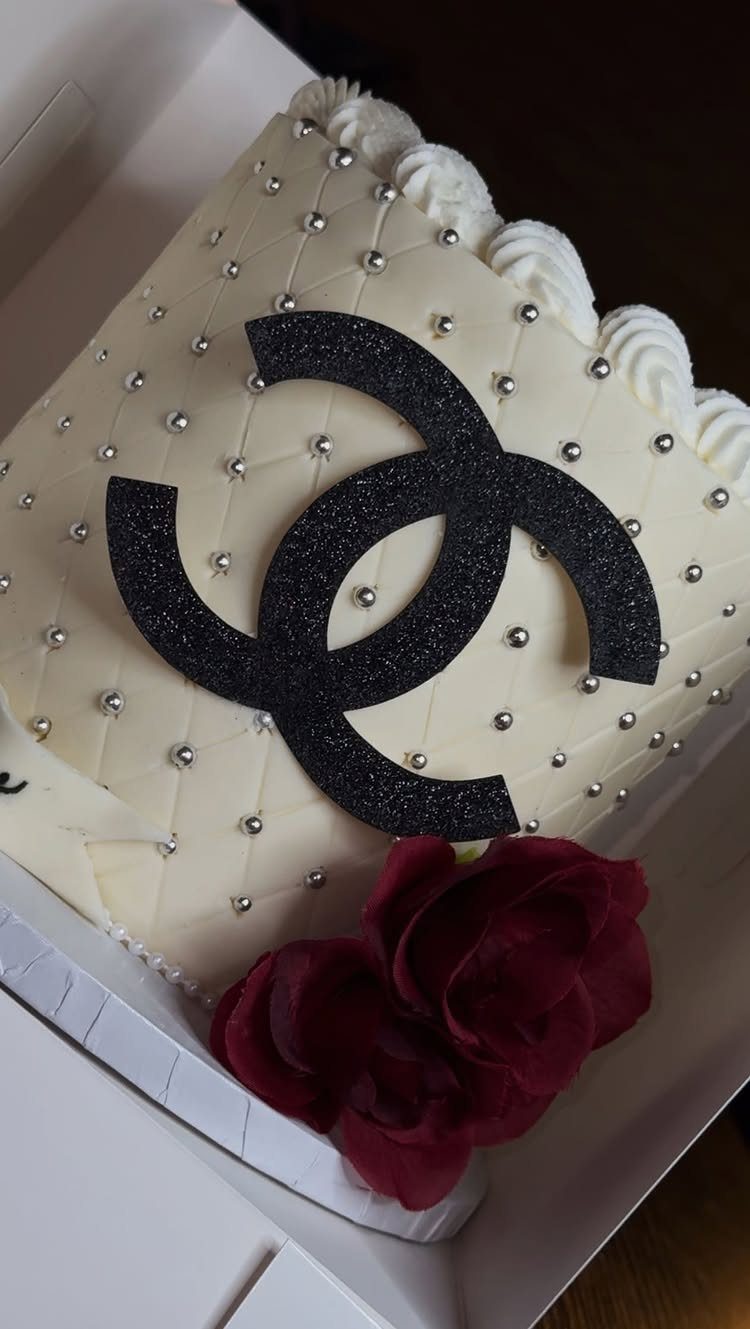 White quilted cake with silver pearls, black glitter logo, and a red rose.