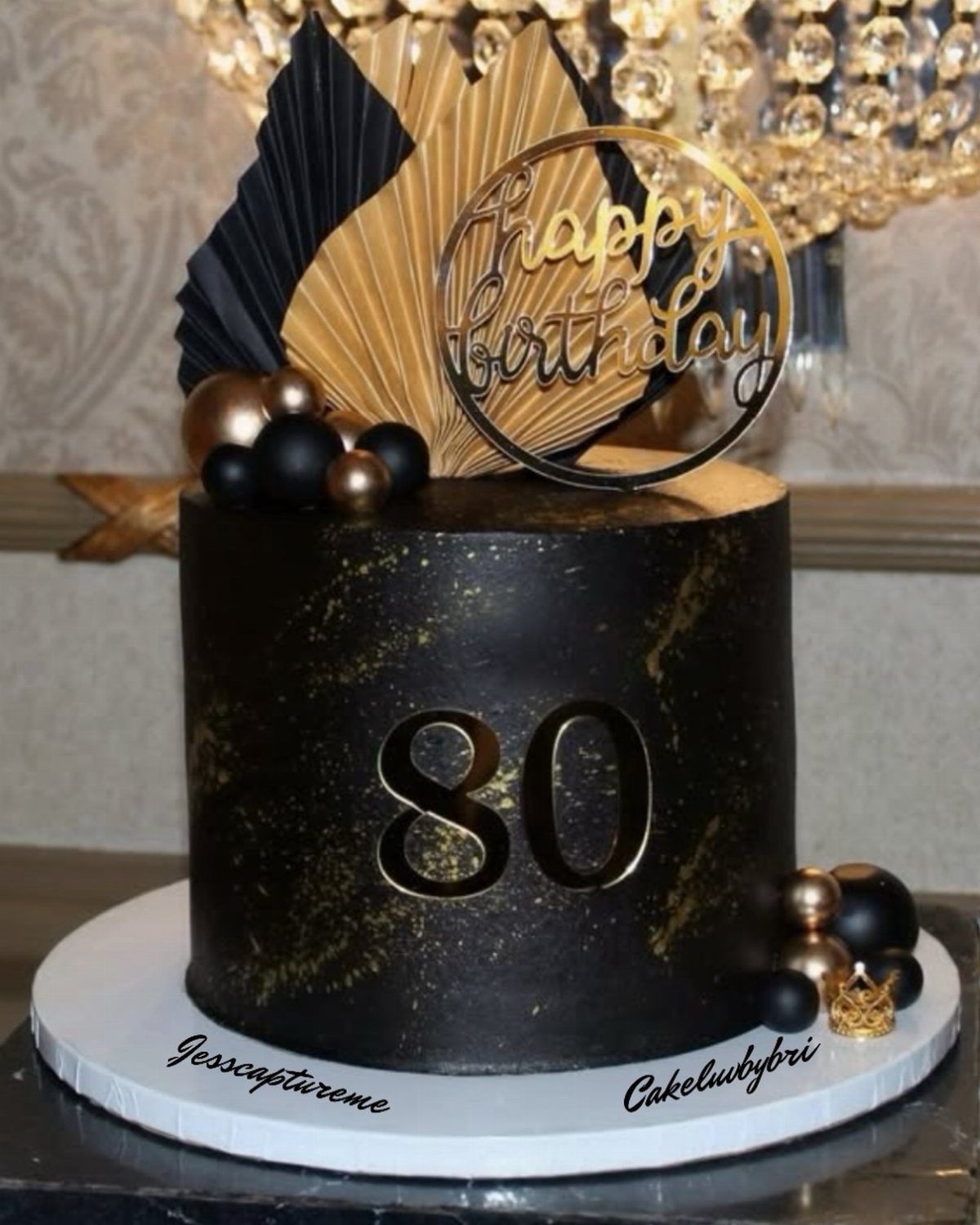 Black and gold 80th birthday cake with gold number 80 and decorative topper.