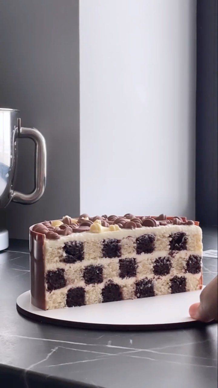 Checkerboard cake with alternating chocolate and vanilla squares topped with chocolate spheres.