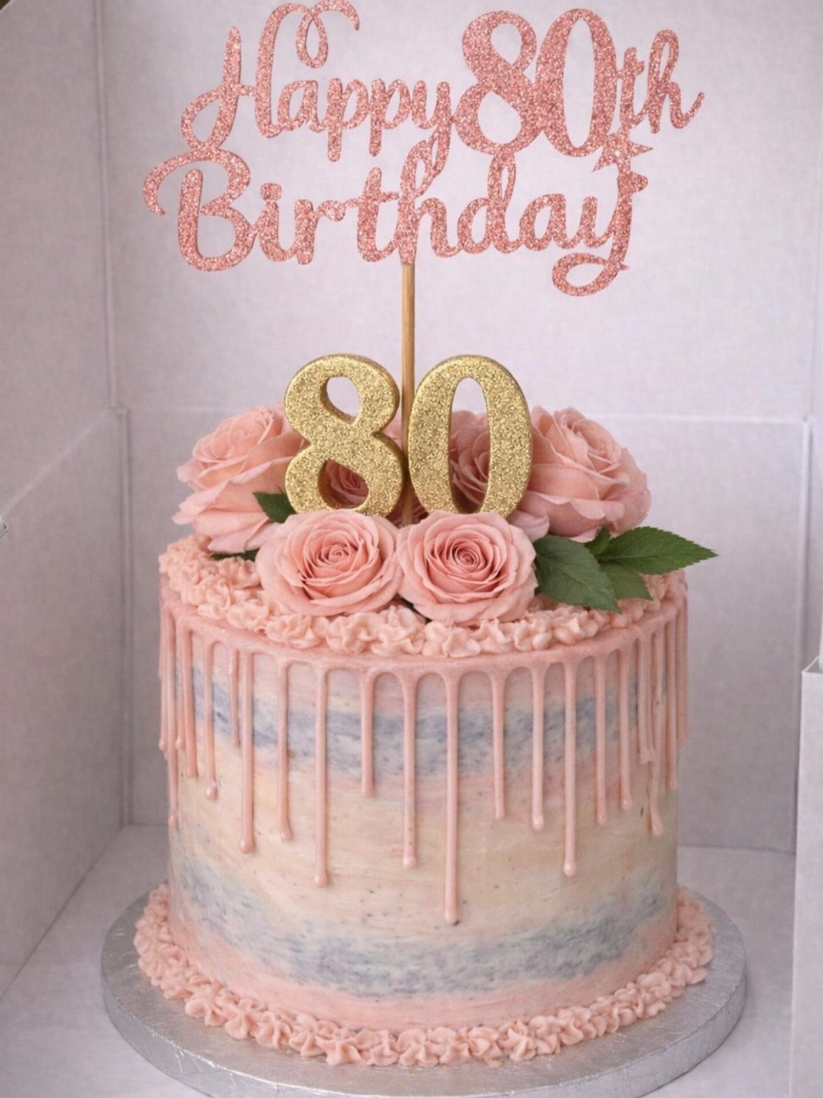 Round marbled cake with pink drip, buttercream roses, and 80th birthday toppers.