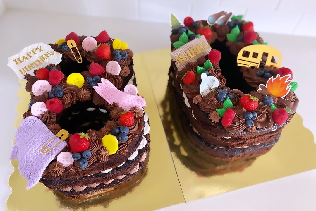 Chocolate number 80 birthday cakes decorated with fresh berries and colorful candies.