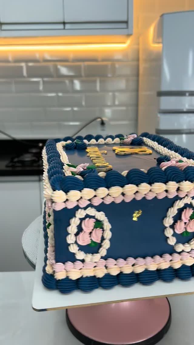 Navy blue square cake with pink frosting and a gold 80 topper.