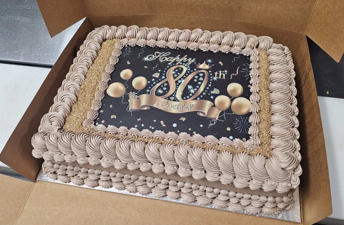 Rectangular sheet cake with tan frosting and a Happy 80th Birthday edible topper.