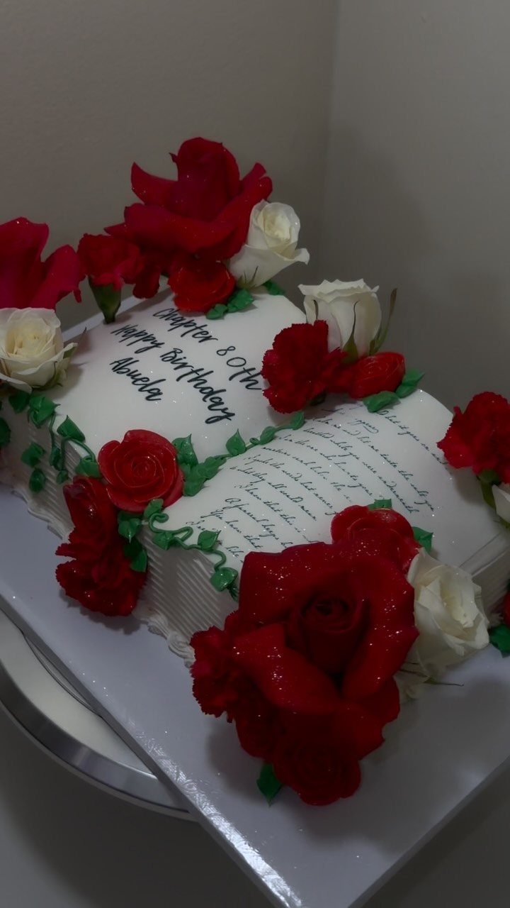 Open book shaped cake with red and white roses for an 80th birthday.