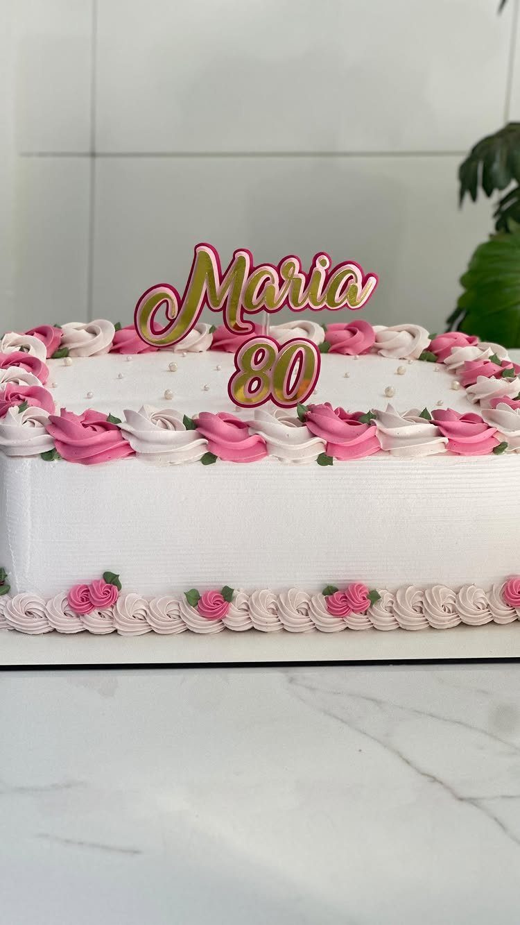 White sheet cake with pink frosting roses and a Maria 80 cake topper.