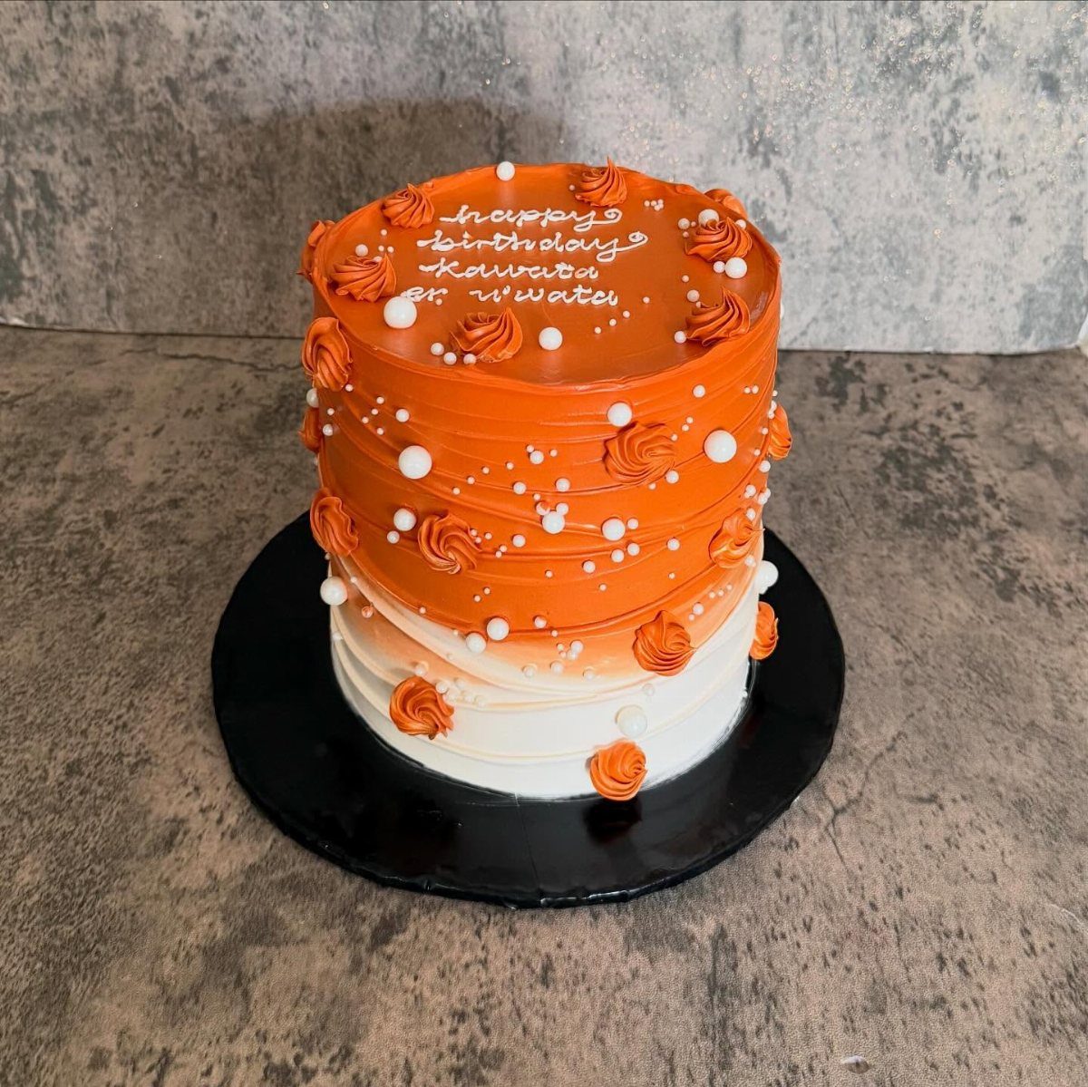 Orange and white ombre cake with buttercream swirls and white pearl decorations.