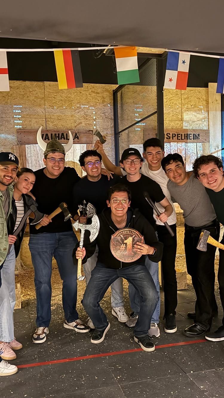 Group of teenagers posing with axes and a medal at an axe throwing venue.