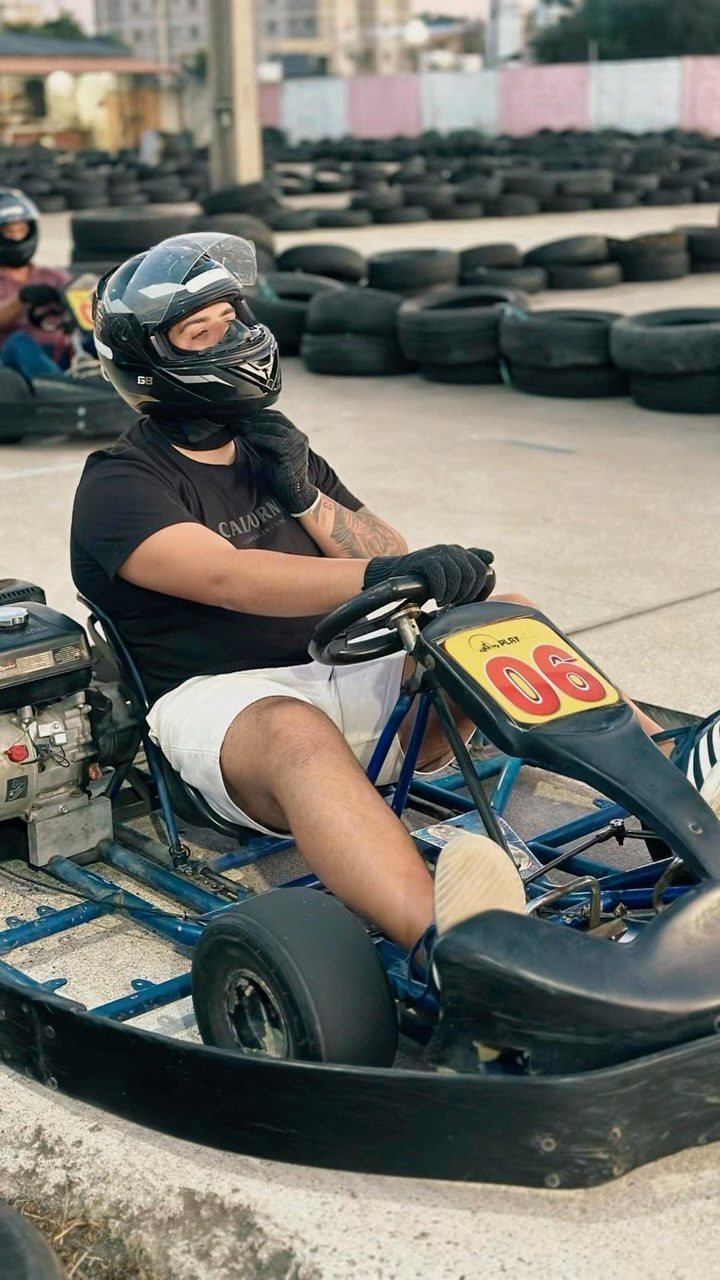 Young man in a helmet sitting in a go-kart on a racing track.