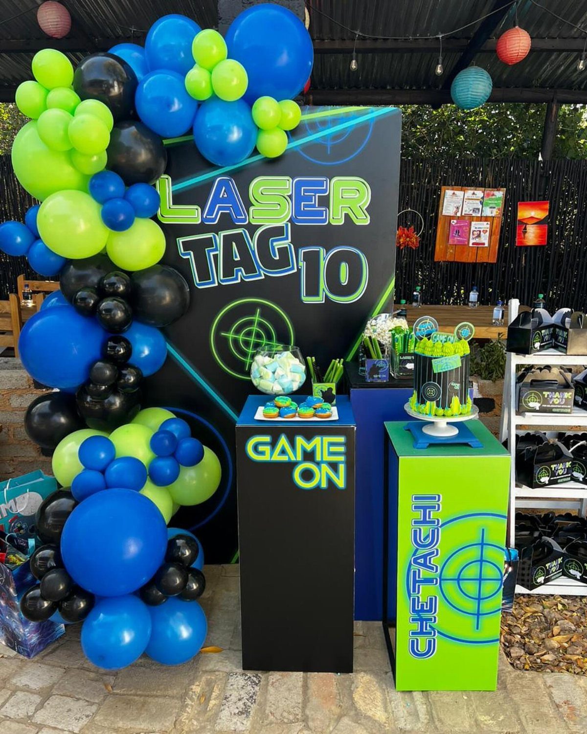 Laser tag themed birthday party setup with blue and green balloons and cake.