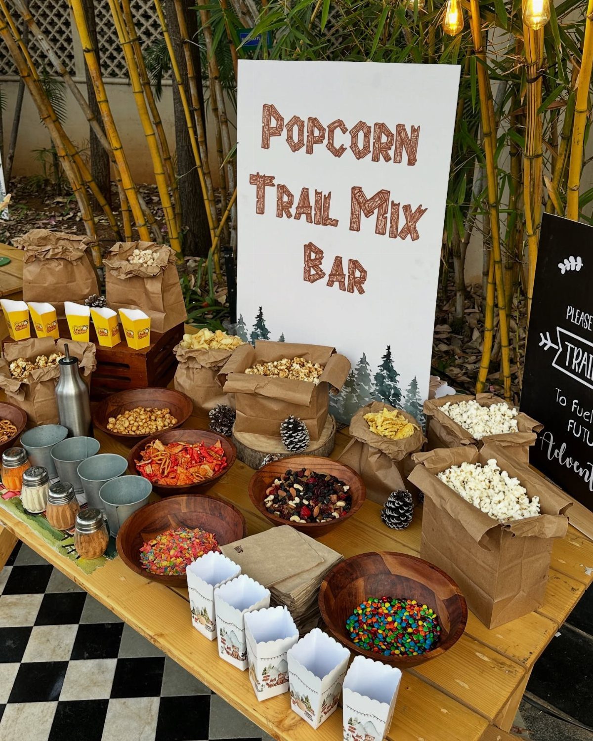 Popcorn trail mix bar with various snacks in bowls and bags on wooden table