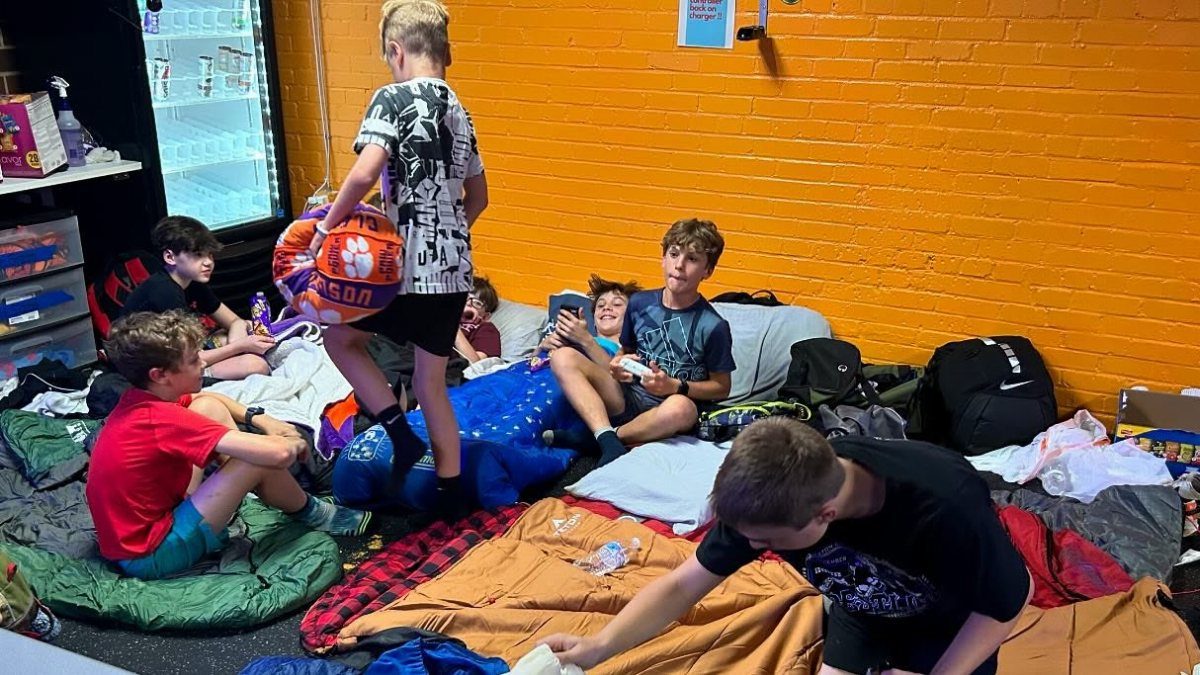 Teenage boys hanging out on sleeping bags in a room with orange walls.