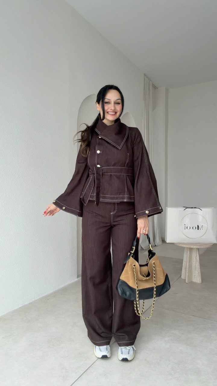 Woman wearing a dark brown denim co-ord set with a structured jacket and trousers.