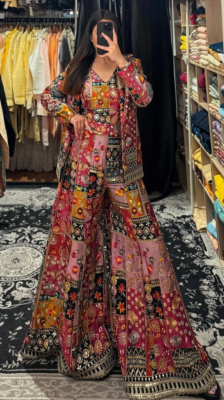 Woman wearing a colorful embroidered traditional outfit with wide-leg trousers in a store