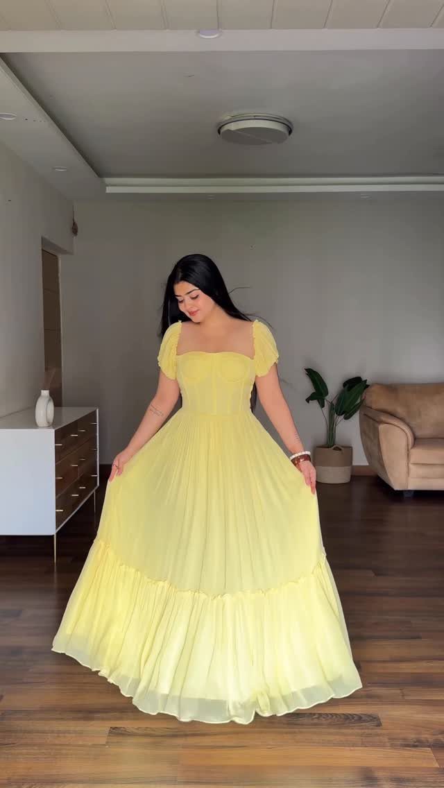 Woman wearing a long flowing yellow gown with puffed sleeves in a living room